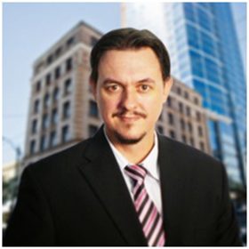 Handsome businessman posing for the camera with office buildings in the background